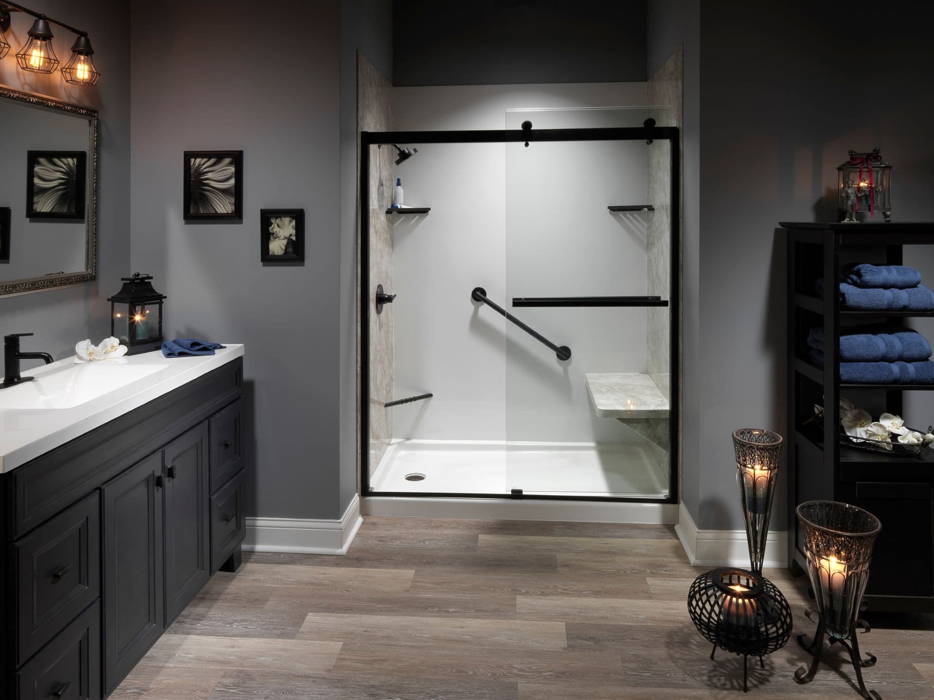 A gray bathroom with a walk-in shower with sliding glass doors, built-in shower bench, and a grab safety bar.